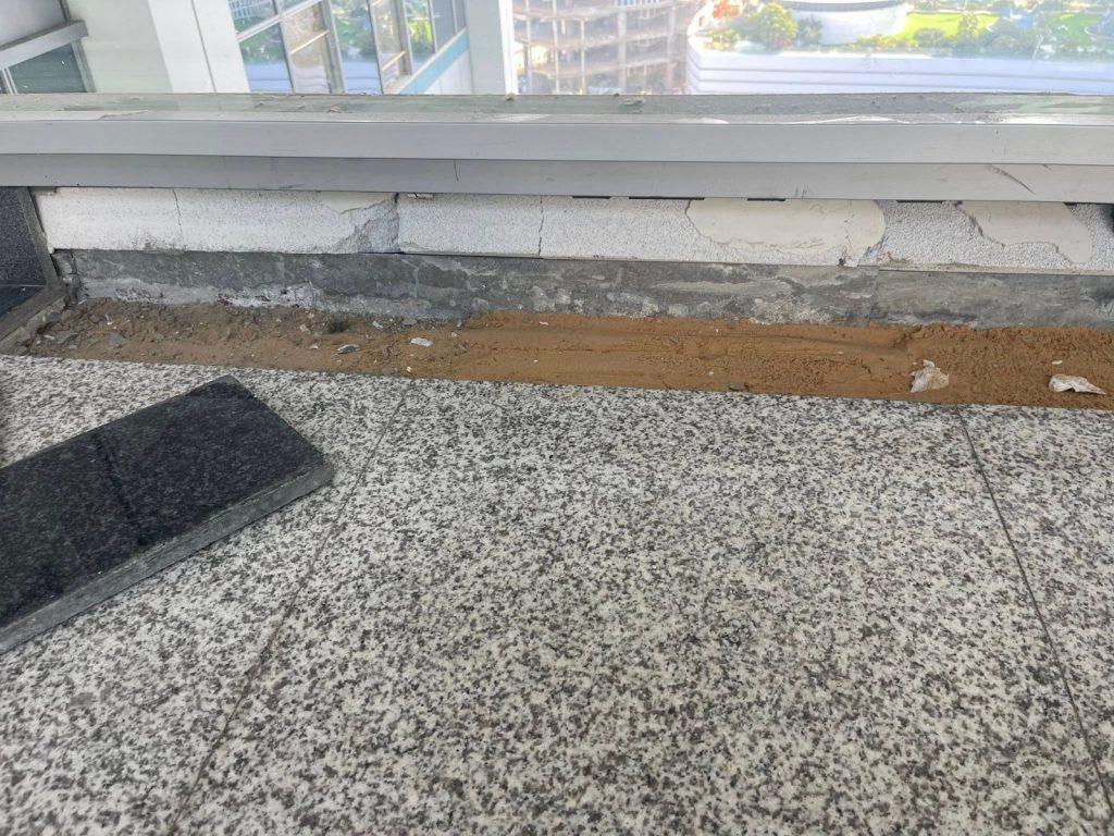 השלמת ריצוף גרניט בקו החלון, מצע חול לפני הנחת האריח האחרון