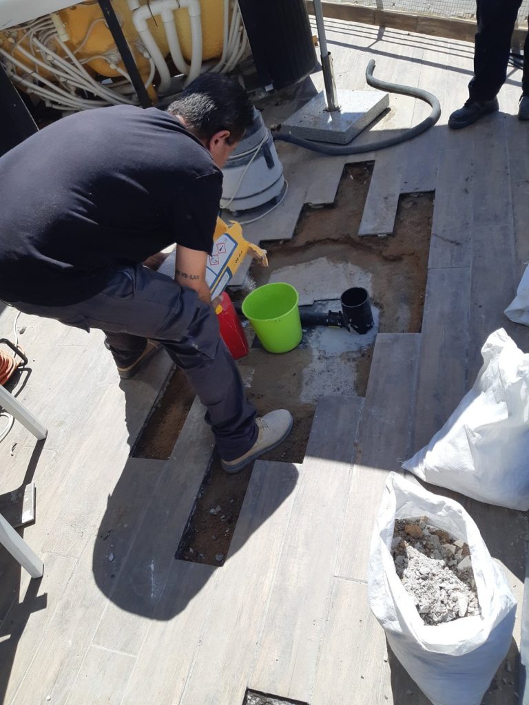 פירוק אריחים במרפסת לאיתור נזילה ויישום שכבת איטום סביב נקז